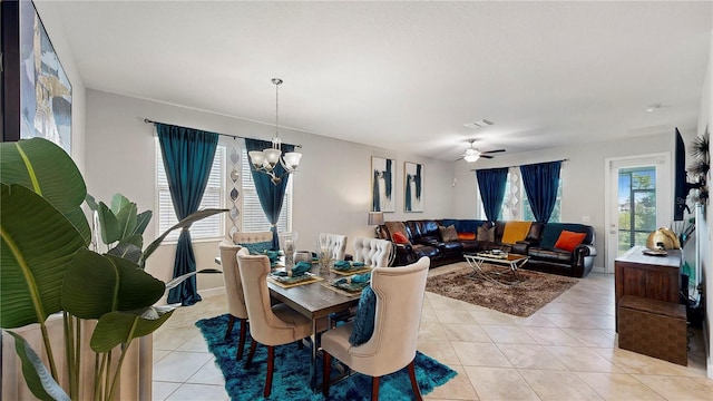 tiled dining room with ceiling fan with notable chandelier