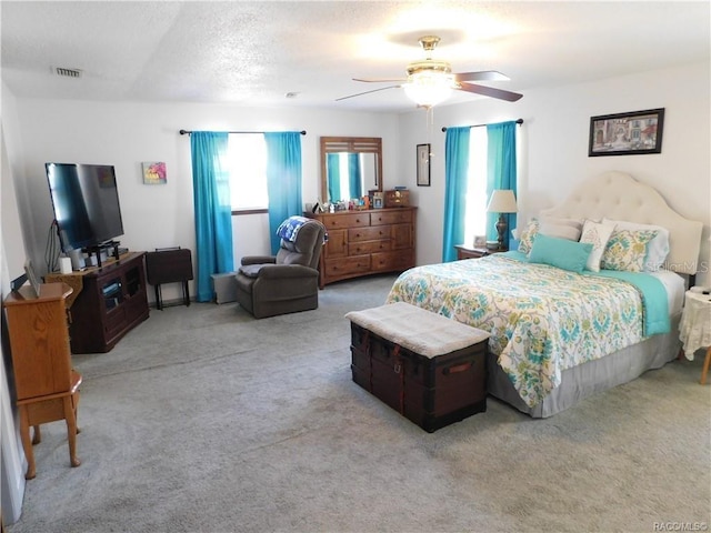 carpeted bedroom featuring ceiling fan and a textured ceiling