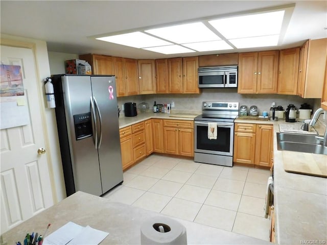 kitchen with light tile patterned flooring, appliances with stainless steel finishes, sink, and backsplash