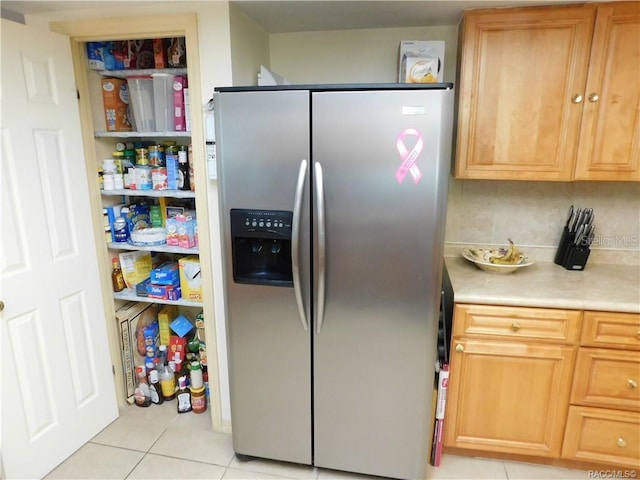 interior space featuring light tile patterned floors, backsplash, and stainless steel fridge with ice dispenser