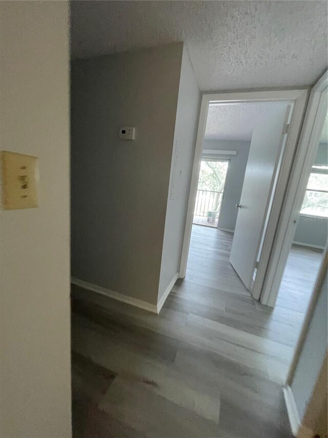 hall featuring light wood-type flooring and a textured ceiling