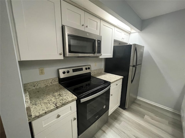 kitchen with white cabinetry, light stone countertops, light hardwood / wood-style flooring, and stainless steel appliances