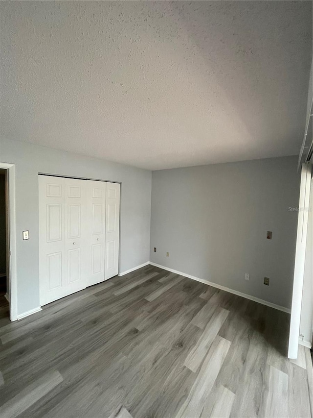 unfurnished bedroom featuring hardwood / wood-style flooring, a closet, and a textured ceiling