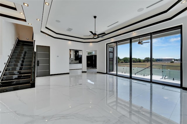 unfurnished living room with ceiling fan and a raised ceiling