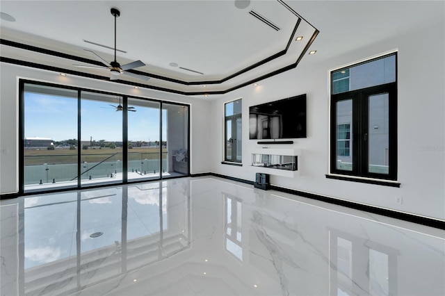 unfurnished living room featuring ceiling fan and a tray ceiling