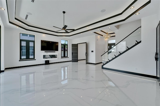 unfurnished living room featuring a raised ceiling and ceiling fan