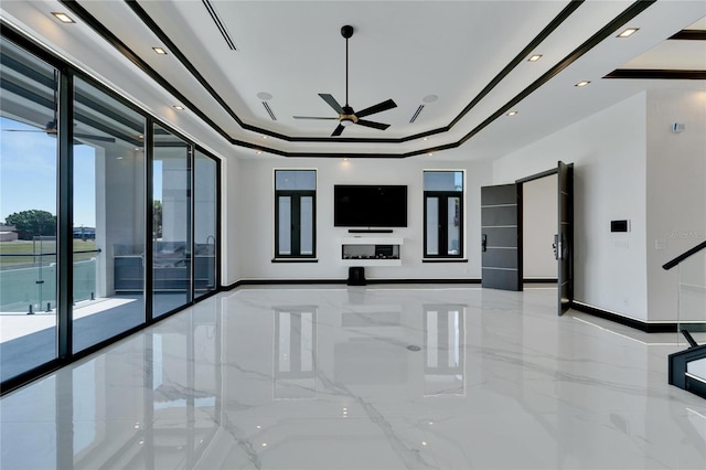 unfurnished living room with ceiling fan and a tray ceiling