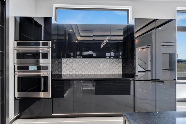 kitchen featuring decorative backsplash, stainless steel double oven, and dark stone countertops