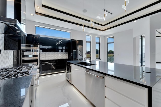 kitchen with white cabinetry, a raised ceiling, tasteful backsplash, range hood, and sink