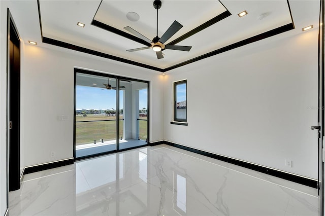 spare room with ceiling fan and a raised ceiling