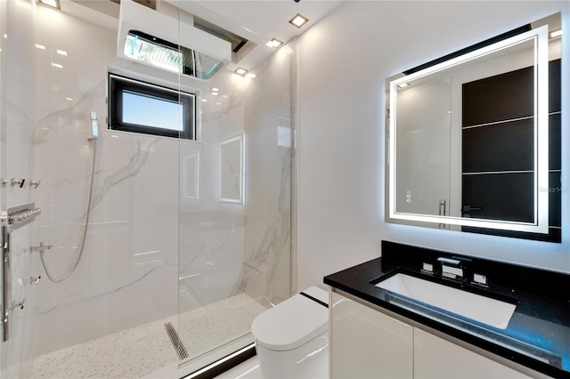 bathroom with toilet, vanity, and a tile shower