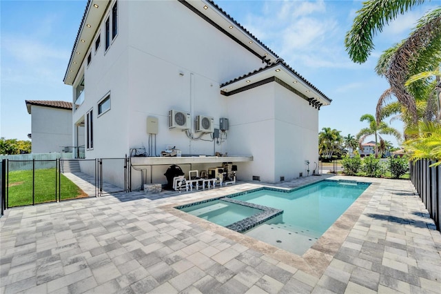 rear view of property with a swimming pool with hot tub, ac unit, and exterior bar