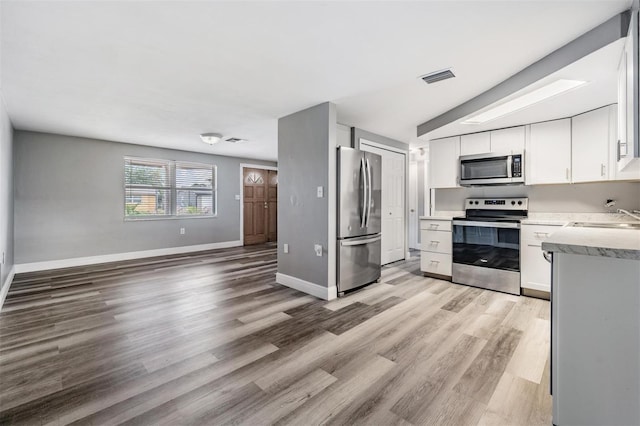 kitchen featuring sink, appliances with stainless steel finishes, light wood-type flooring, and white cabinetry