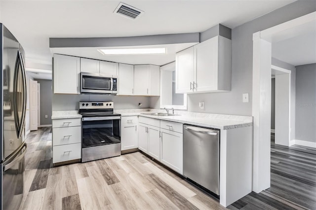 kitchen featuring white cabinetry, light wood-type flooring, and stainless steel appliances