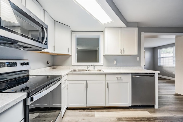 kitchen featuring sink, light hardwood / wood-style flooring, white cabinets, and stainless steel appliances