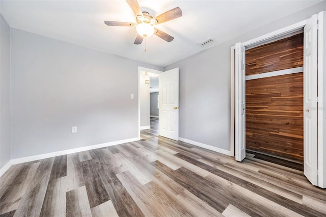 unfurnished bedroom featuring ceiling fan, hardwood / wood-style flooring, and a closet