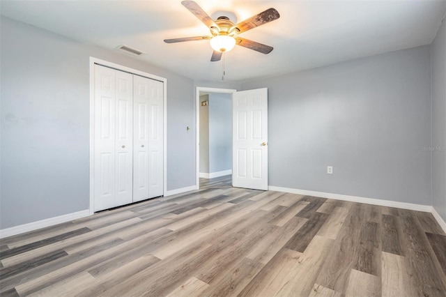 unfurnished bedroom with wood-type flooring, a closet, and ceiling fan