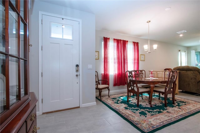 entryway featuring light tile patterned floors, plenty of natural light, and a notable chandelier