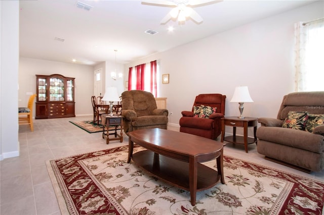 tiled living room featuring ceiling fan with notable chandelier