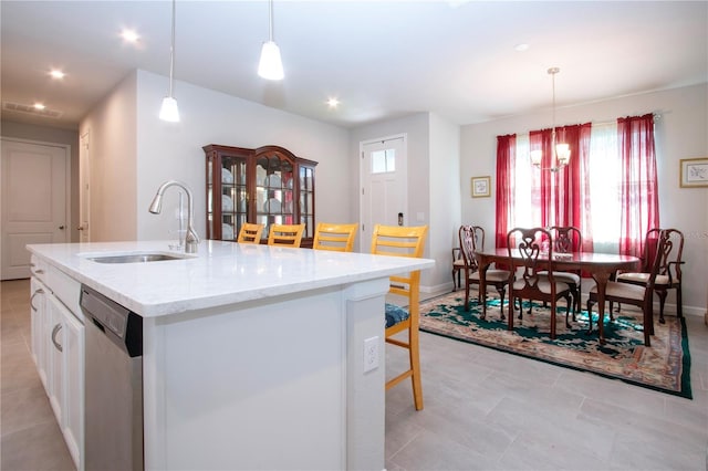 kitchen with decorative light fixtures, dishwasher, sink, a kitchen island with sink, and white cabinets