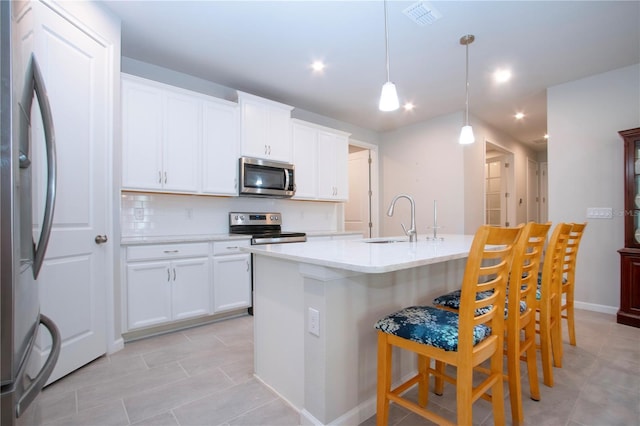 kitchen featuring stainless steel appliances, sink, white cabinets, and decorative light fixtures