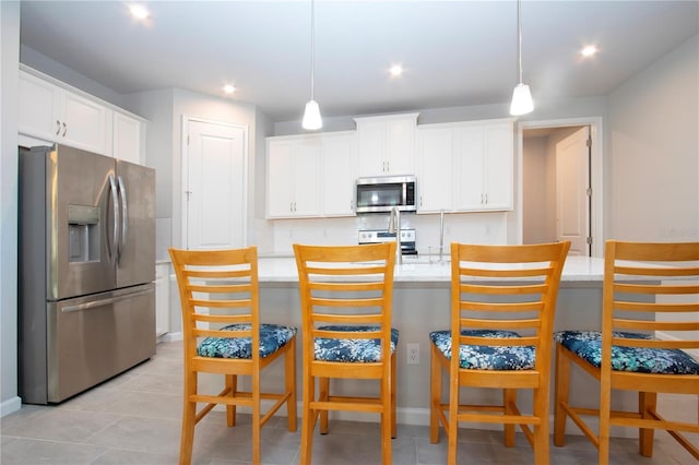 kitchen with white cabinetry, pendant lighting, stainless steel appliances, and an island with sink