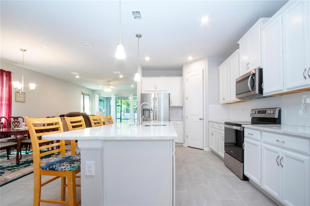 kitchen featuring stainless steel appliances, decorative backsplash, a kitchen bar, and a kitchen island with sink