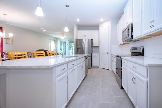 kitchen featuring decorative light fixtures, stainless steel appliances, and a kitchen island with sink