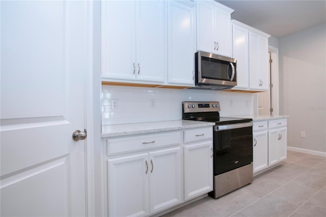 kitchen featuring light stone countertops, appliances with stainless steel finishes, white cabinetry, tasteful backsplash, and light tile patterned floors