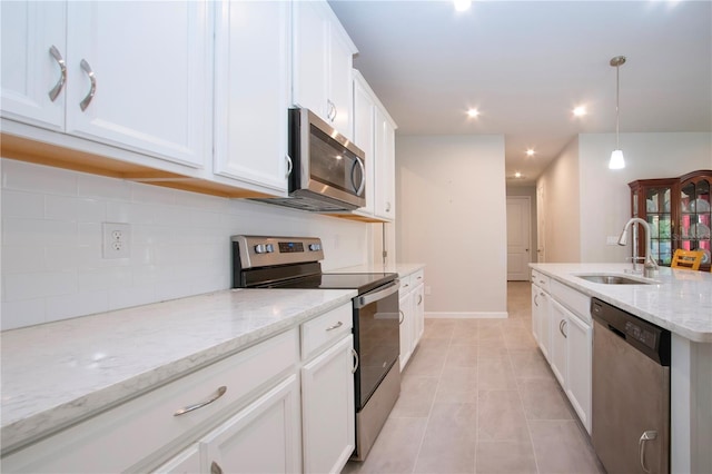 kitchen featuring sink, hanging light fixtures, light stone countertops, appliances with stainless steel finishes, and white cabinets