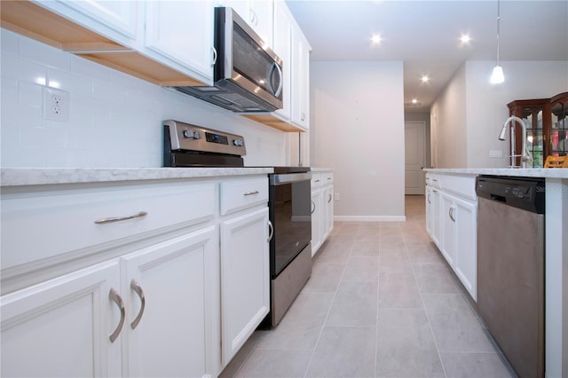 kitchen with light tile patterned flooring, appliances with stainless steel finishes, white cabinets, and decorative light fixtures