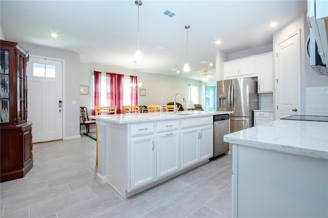 kitchen with white cabinets, appliances with stainless steel finishes, sink, hanging light fixtures, and a kitchen island with sink