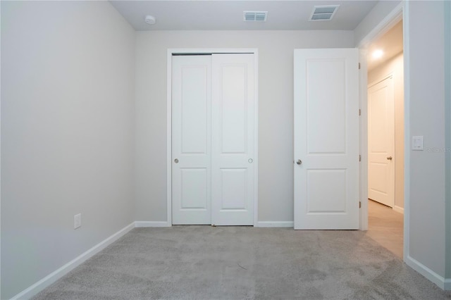 unfurnished bedroom with a closet and light colored carpet