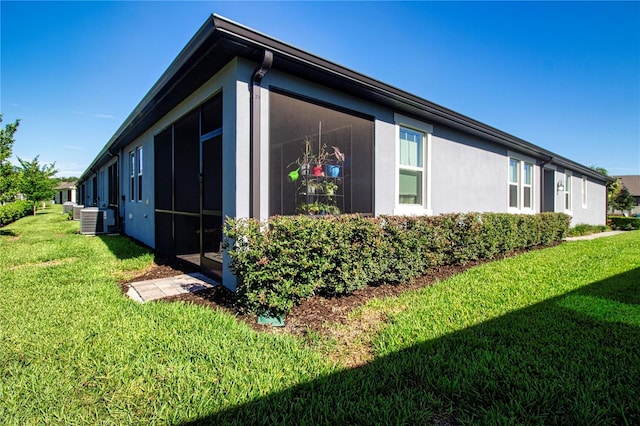 view of home's exterior with a sunroom, a lawn, and central AC