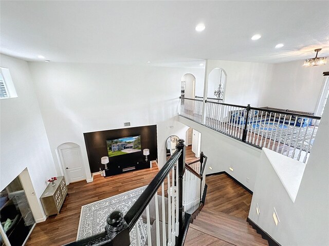 staircase with an inviting chandelier and dark wood-type flooring