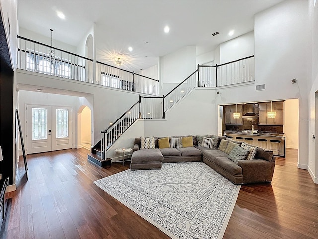 living room with dark wood-type flooring, french doors, and a towering ceiling