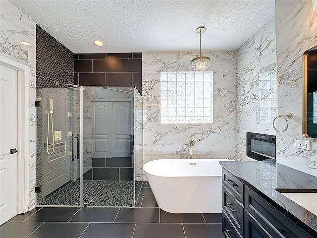 bathroom with a textured ceiling, vanity, tile walls, tile patterned floors, and separate shower and tub