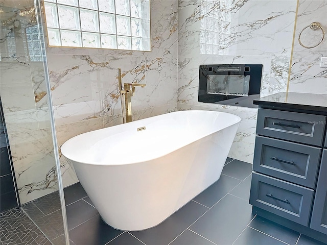 bathroom featuring vanity, tile patterned floors, a tub to relax in, and tile walls