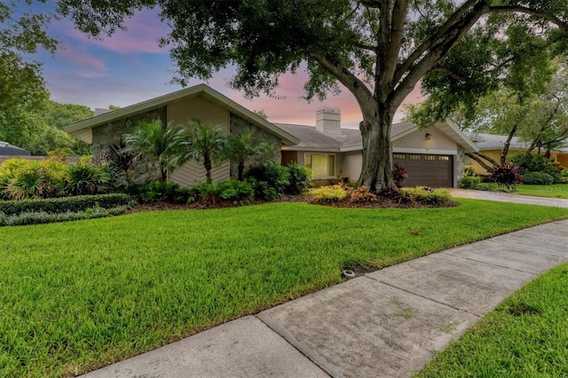 view of front of home with a front lawn, a garage, driveway, and stucco siding