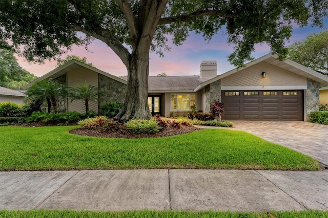 ranch-style home featuring a garage and a lawn