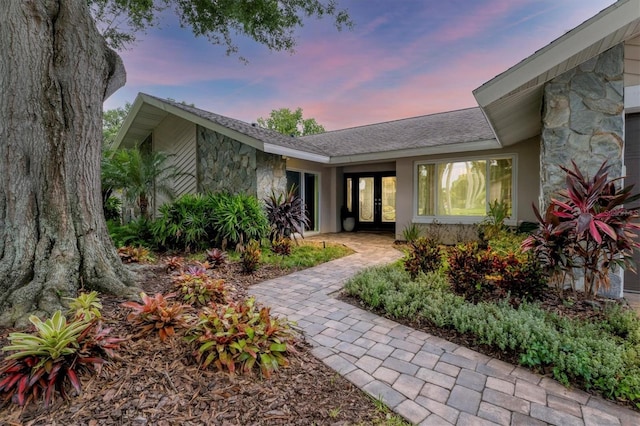 exterior entry at dusk with french doors and stone siding