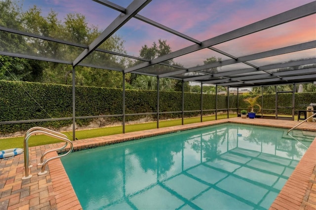 pool at dusk with a fenced in pool, glass enclosure, and a patio