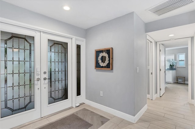 foyer entrance with light wood finished floors, visible vents, french doors, and baseboards