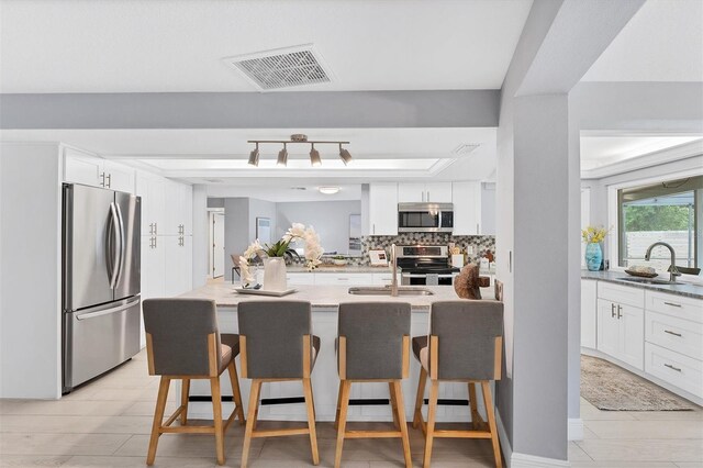 kitchen with light hardwood / wood-style flooring, tasteful backsplash, stainless steel appliances, and white cabinetry