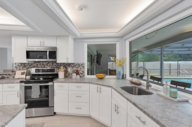 kitchen featuring white cabinetry, decorative backsplash, sink, light stone counters, and appliances with stainless steel finishes