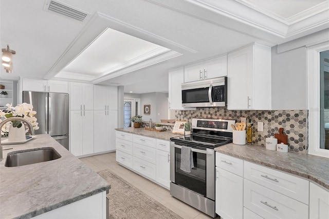 kitchen with visible vents, decorative backsplash, white cabinets, stainless steel appliances, and a sink