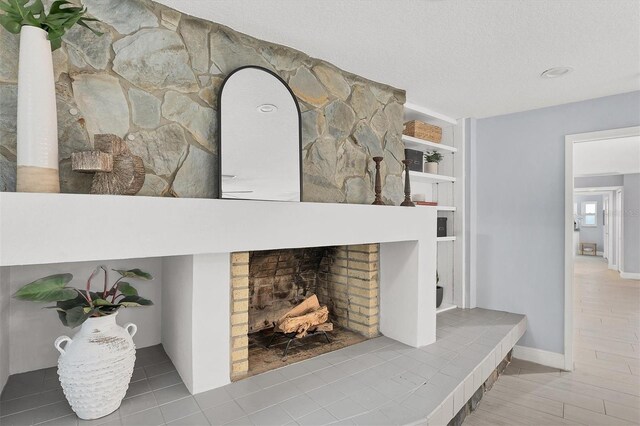 details featuring built in features, a textured ceiling, and a stone fireplace