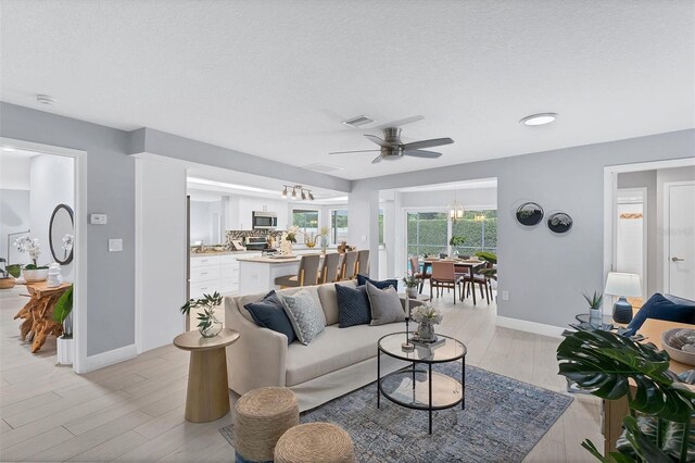 living room featuring light hardwood / wood-style floors, a textured ceiling, and ceiling fan