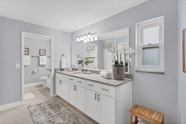 full bath with vanity, toilet, and baseboards