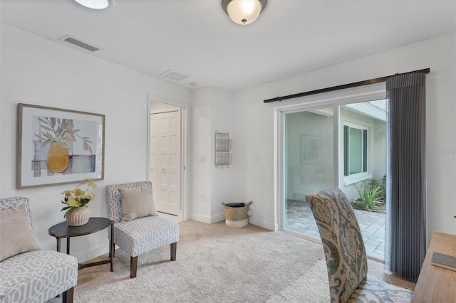 living area featuring visible vents, carpet flooring, and baseboards